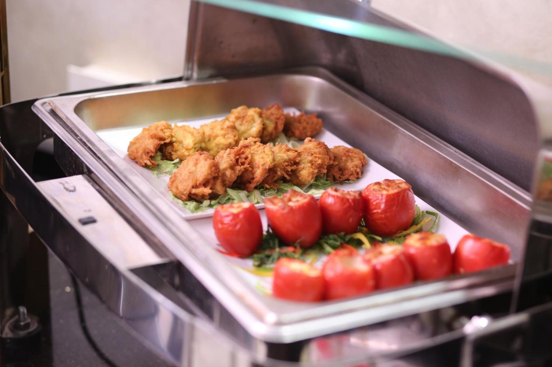 a tray of chicken and tomatoes in an oven at Cairo Taj Hotels & Suites - Dokki in Cairo