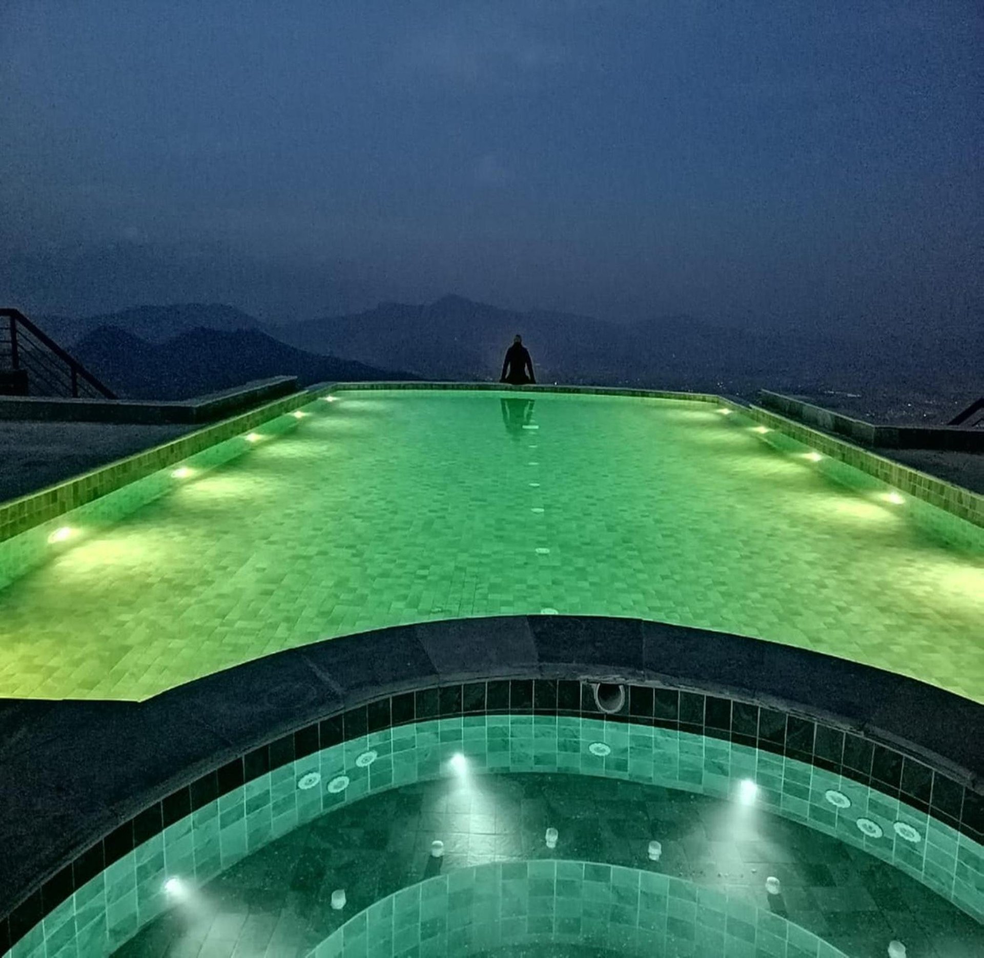 a person standing on top of a green swimming pool at night at Chandragiri Hills Resort Kathmandu-Luxury in the Clouds in Thānkot