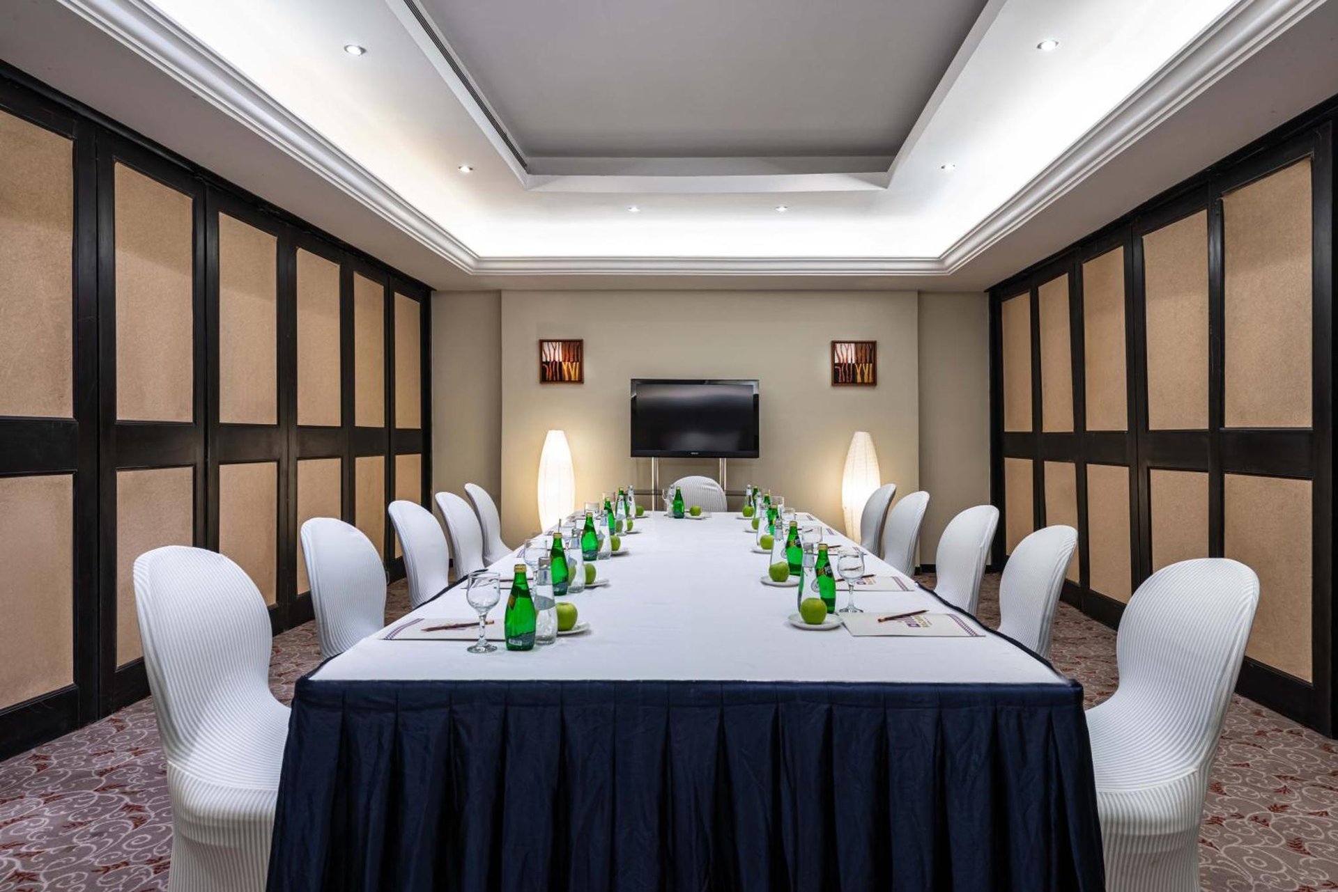 a long table in a room with white chairs at Razana Hotel Al Jubail in Al Jubayl