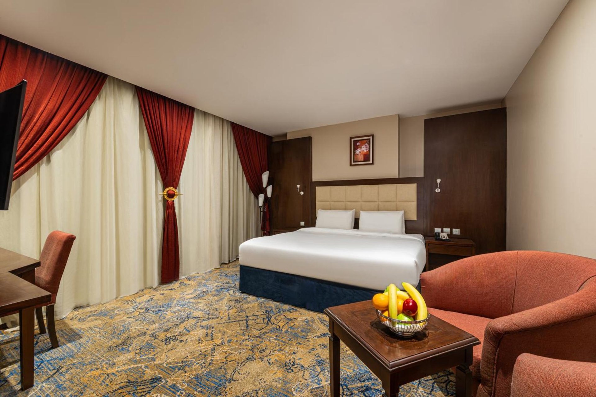 a hotel room with a bed and a chair and a table at Razana Al Rawdha Hotel in Mecca