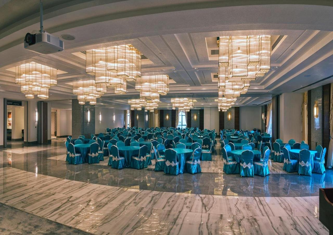 a banquet hall with blue tables and chairs and chandeliers at Boulevard Oman Hotel in Muscat +56 photos