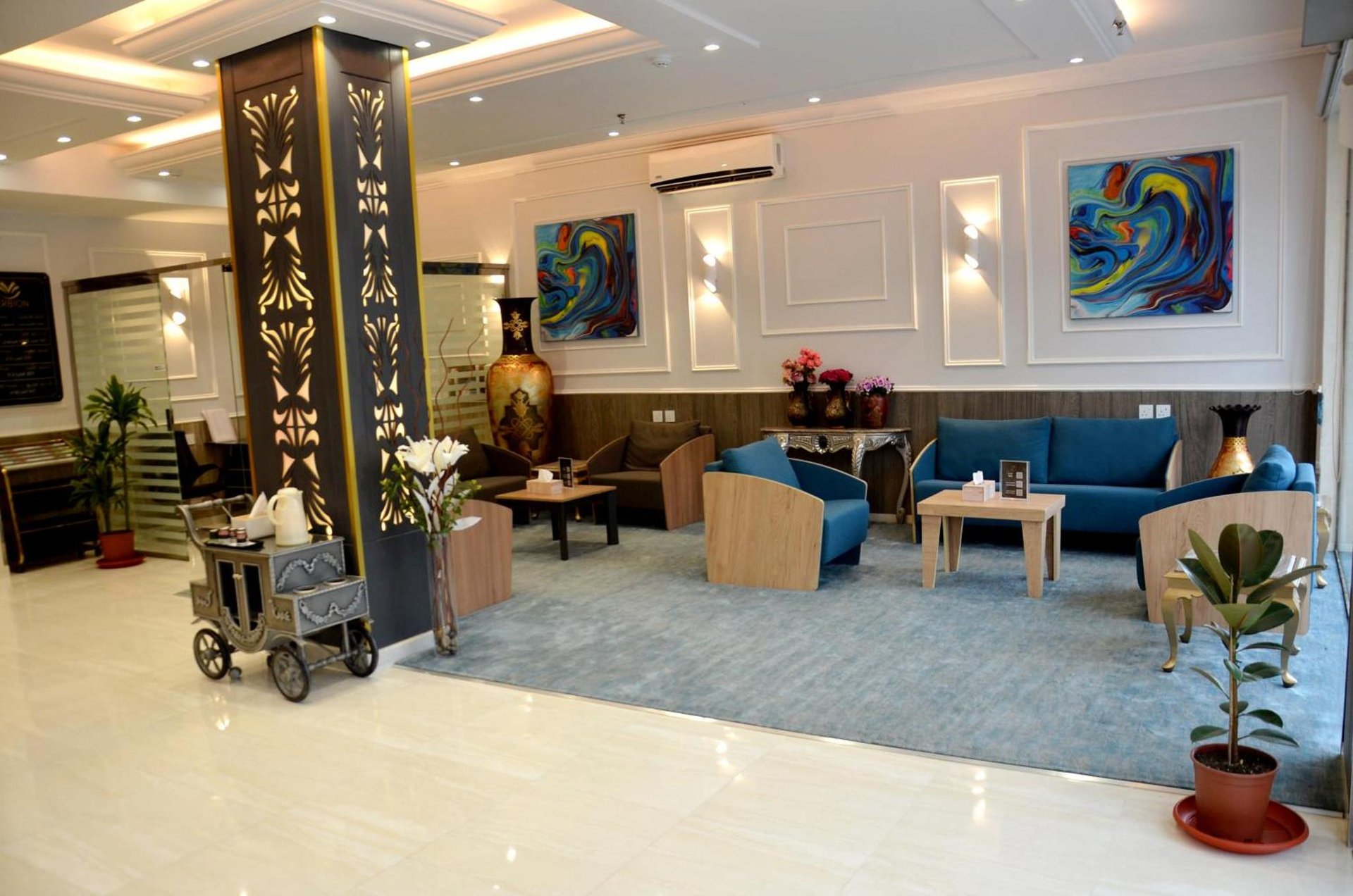 Lobby seating area with patterned decorative columns, abstract wall art, sofa and armchair, coffee table and potted plants at فندق فربيون ابها - Ferbion Hotel Abha in Abha