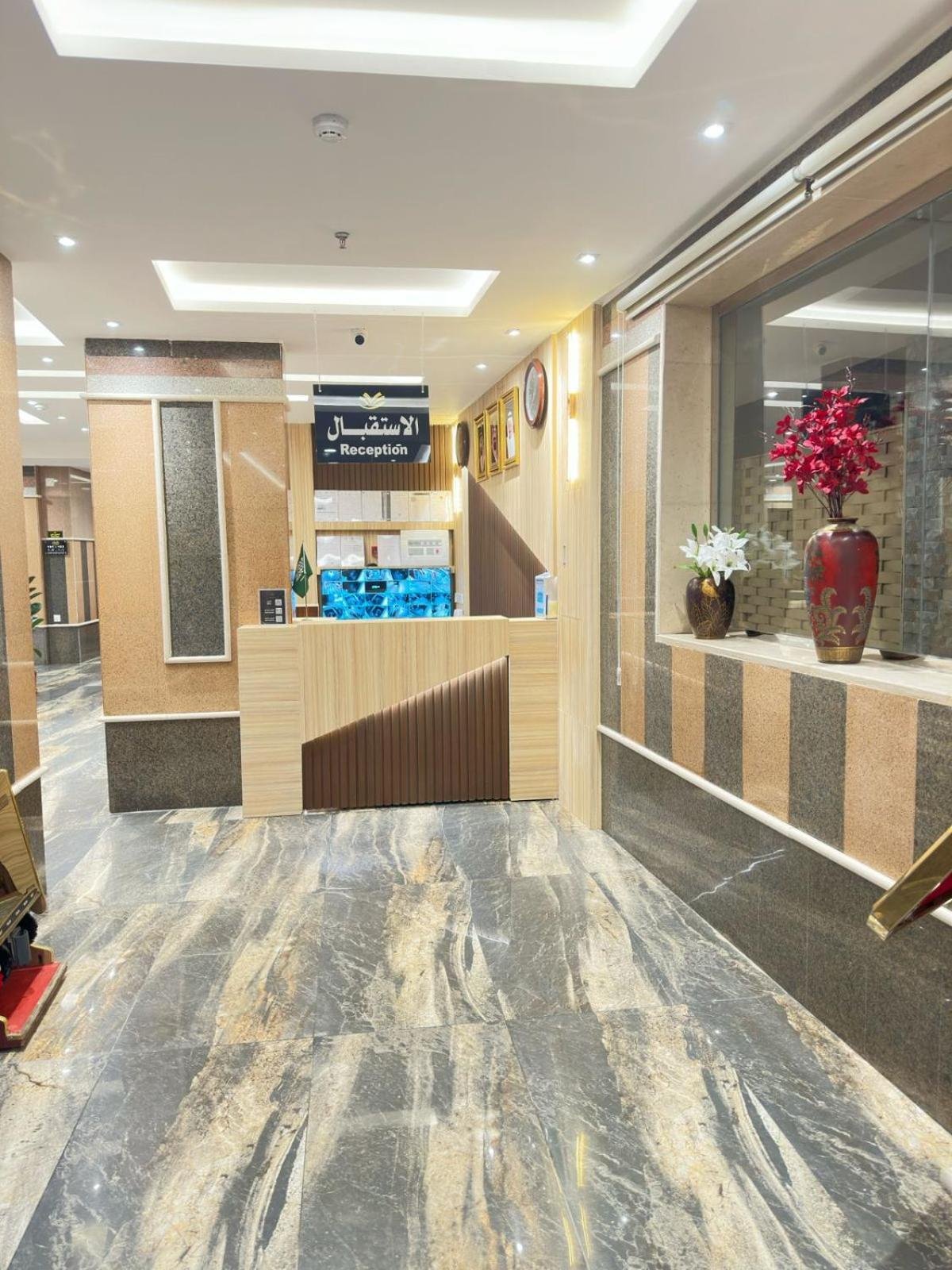 Marble lobby with red-and-gold columns, reception desk with 'الاستقبال' sign and decorative floral arrangement at فربيون للشقق الفندقية ابها-ferbion hotel apartment in Abha