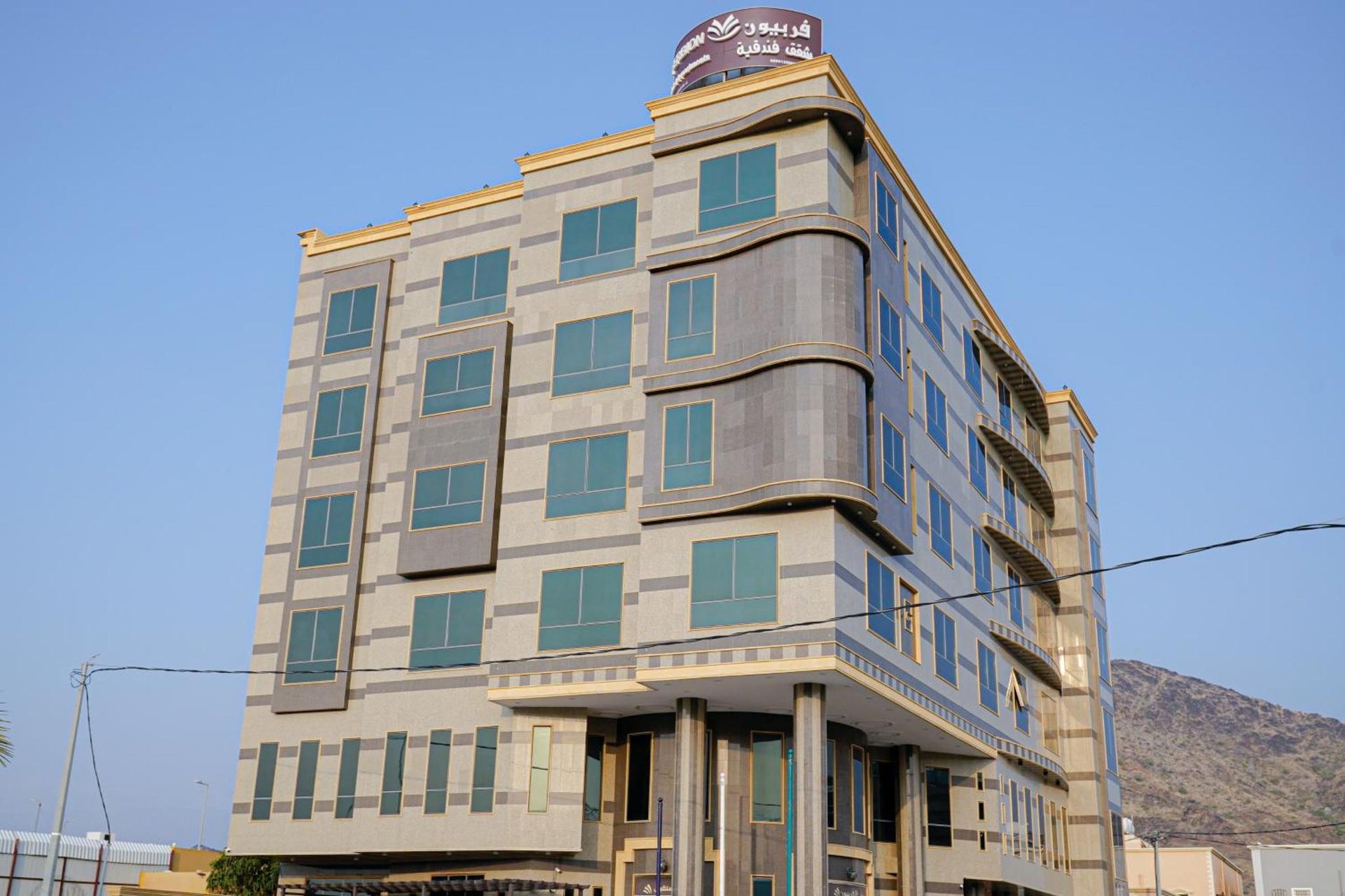 a tall building with a clock on top of it at فربيون للشقق الفندقية محايل in Muhayil