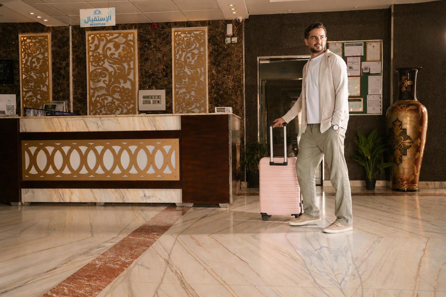 a man standing in a lobby with a suitcase at فربيون للشقق الفندقية محايل in Muhayil