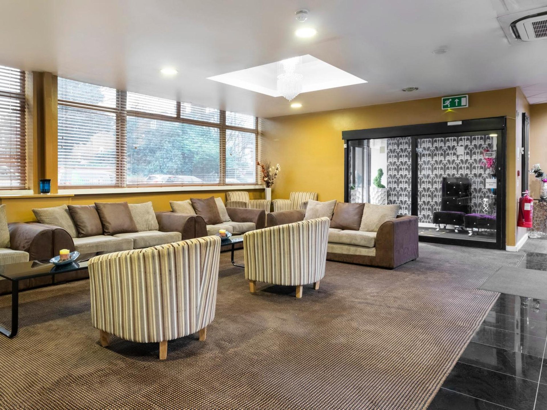 a large living room with couches and tables and chairs at Stuart Hotel in Luton