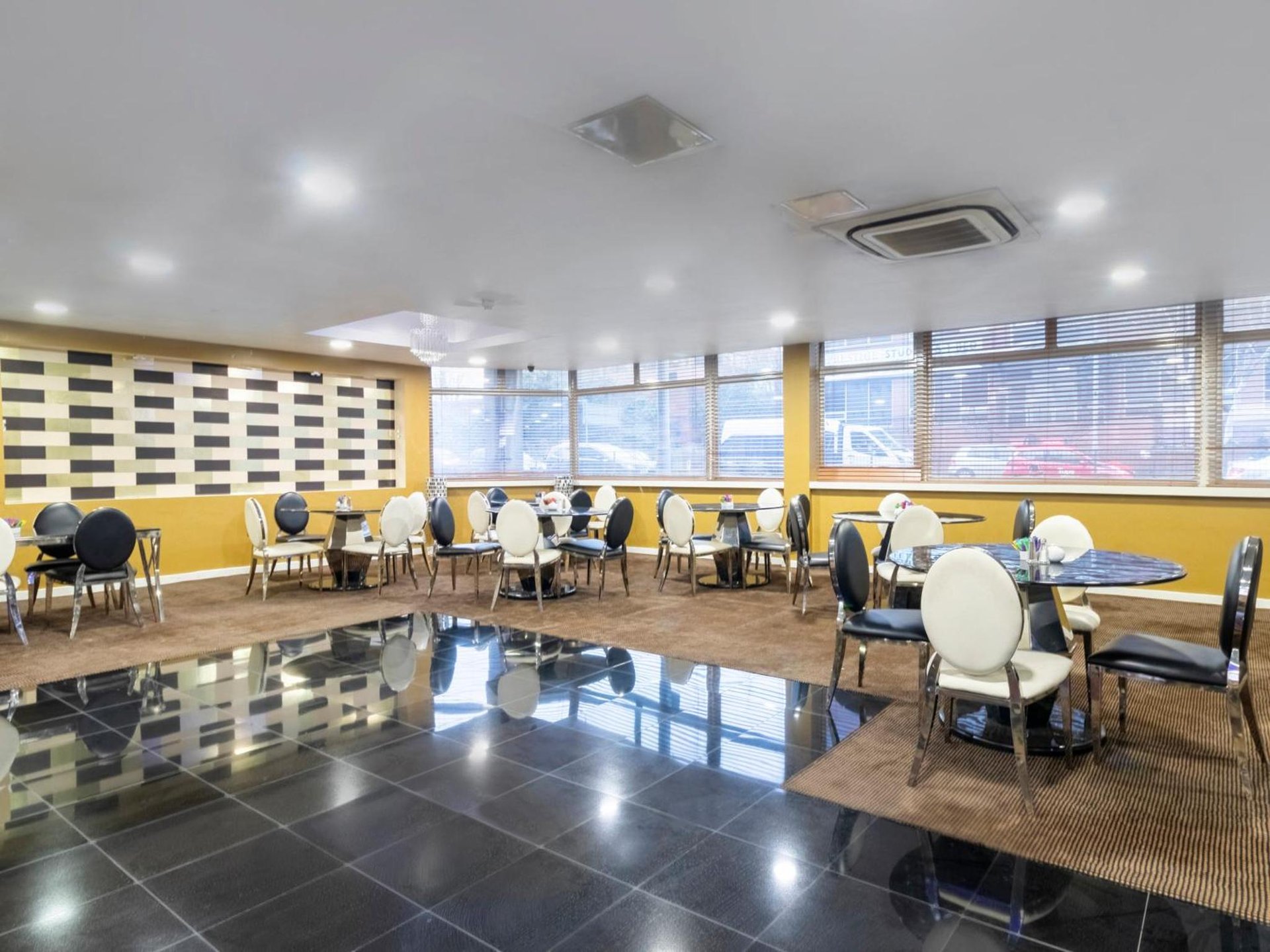 a dining room with tables and chairs and windows at Stuart Hotel in Luton