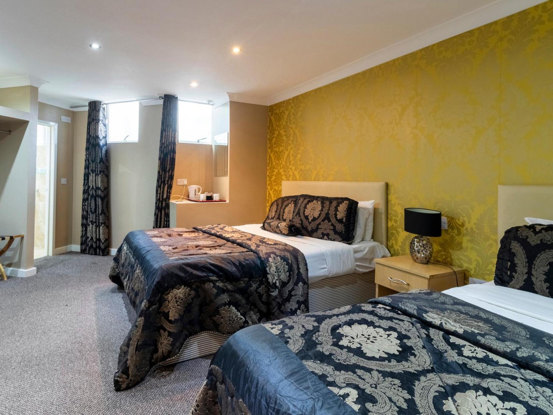 two beds in a room with yellow walls at Stuart Hotel in Luton