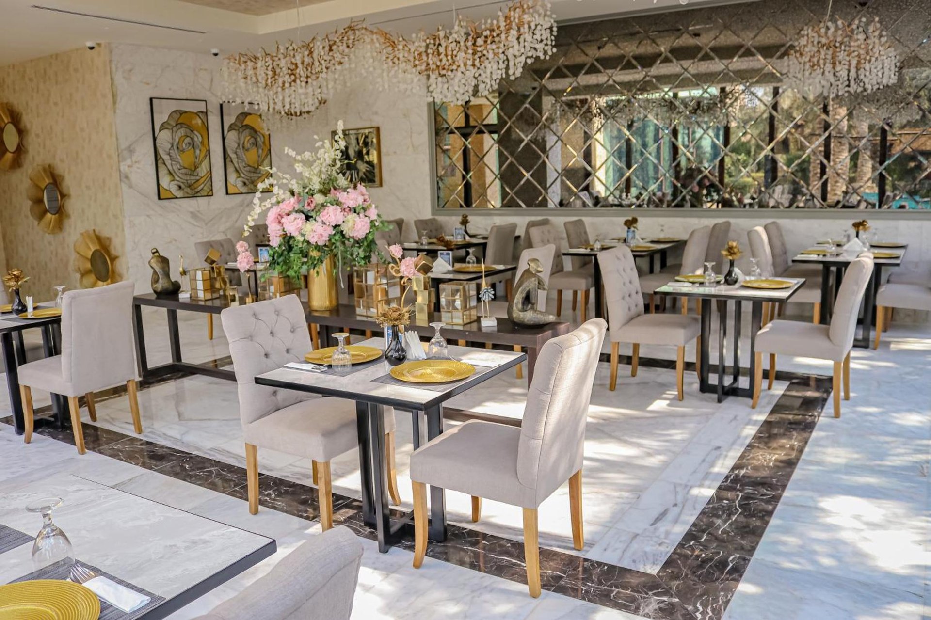 Dining area with tufted chairs, marble floors, gold-rimmed place settings, floral centerpiece and mirrored wall at Lagoona Beach Luxury Resort and Spa in Al Budayyiâ€˜