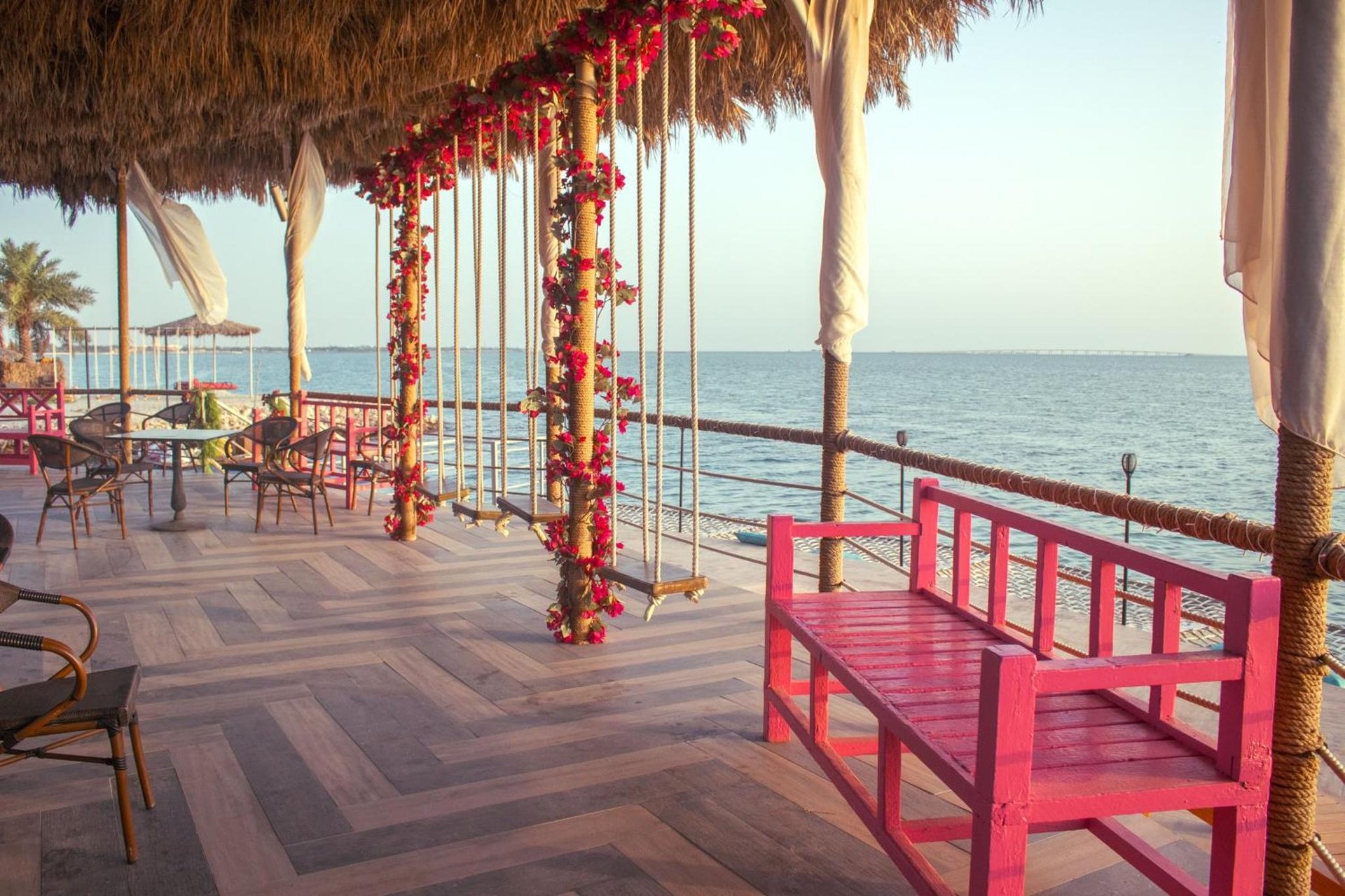 a red bench sitting on a deck overlooking the ocean at Lagoona Beach Luxury Resort and Spa in Manama