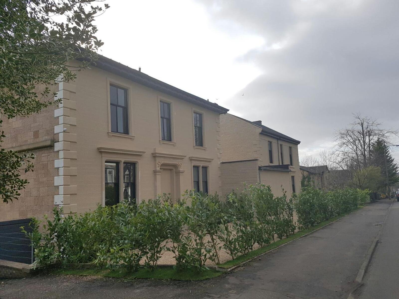 a white house with bushes in front of a street at Crosshill House in Glasgow