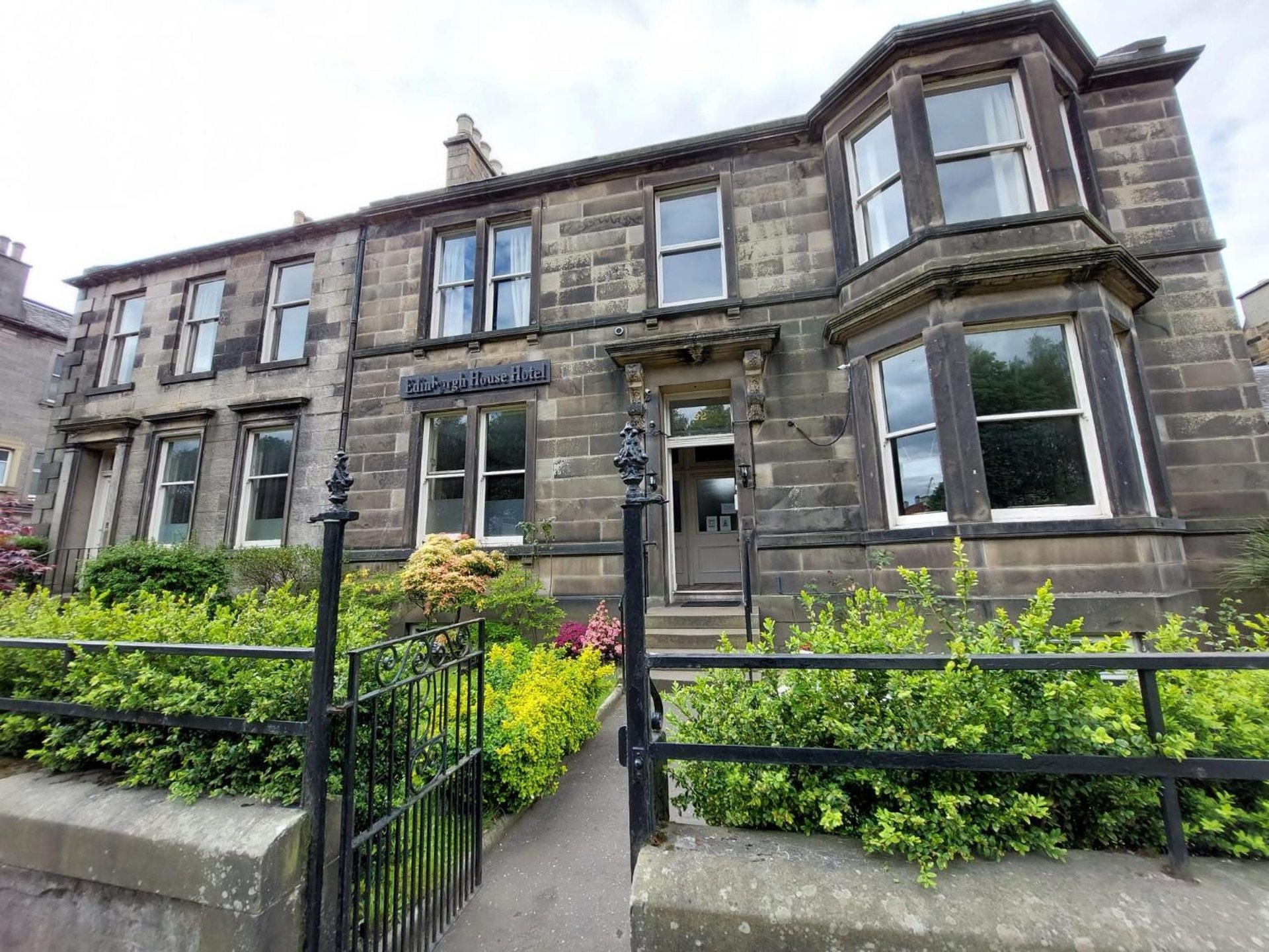 an old stone building with a black fence in front of it at Edinburgh House Hotel in Edinburgh
