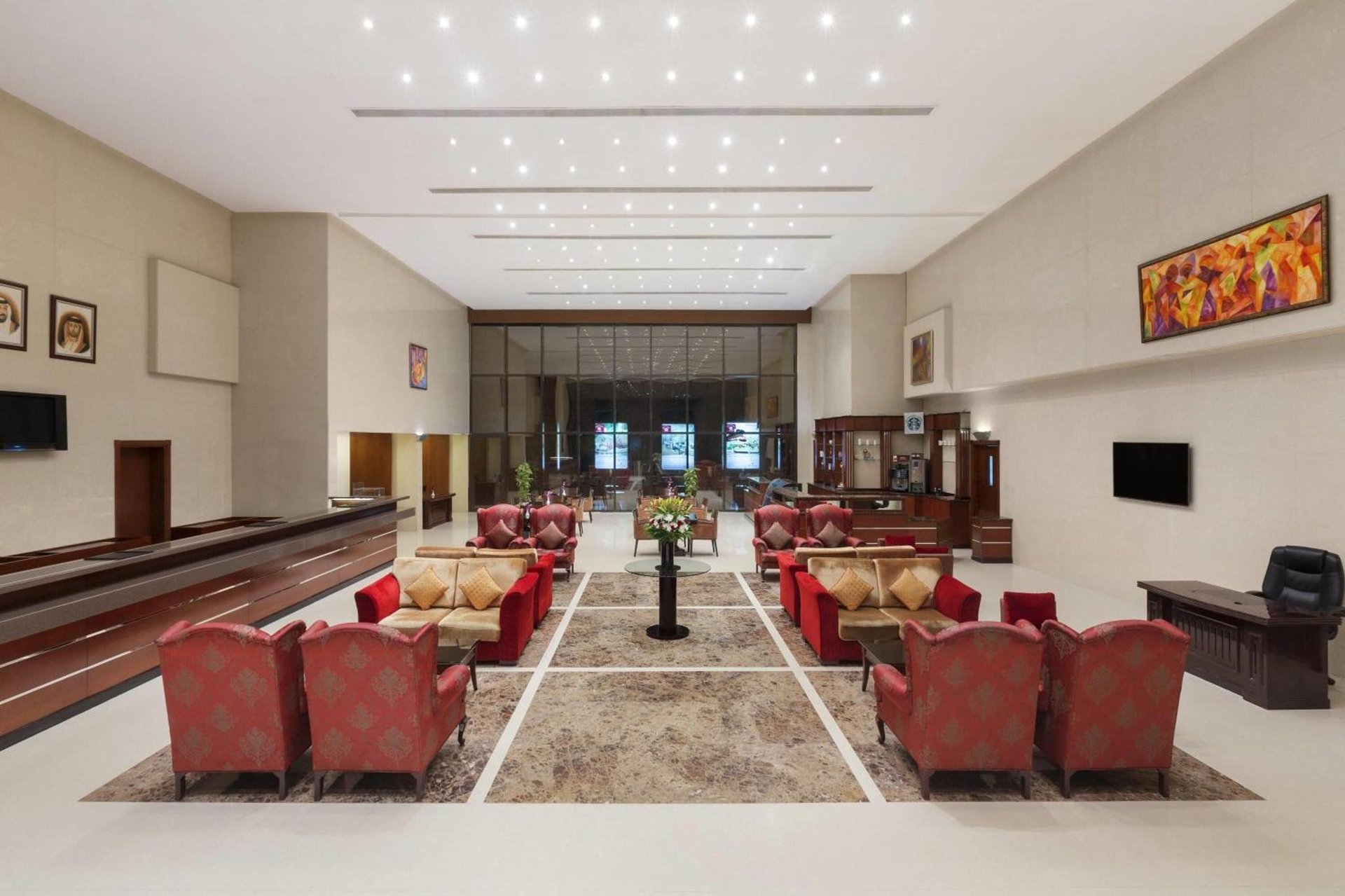 a waiting room with red chairs and a piano at Ramada Hotel & Suites by Wyndham Ajman in Ajman 