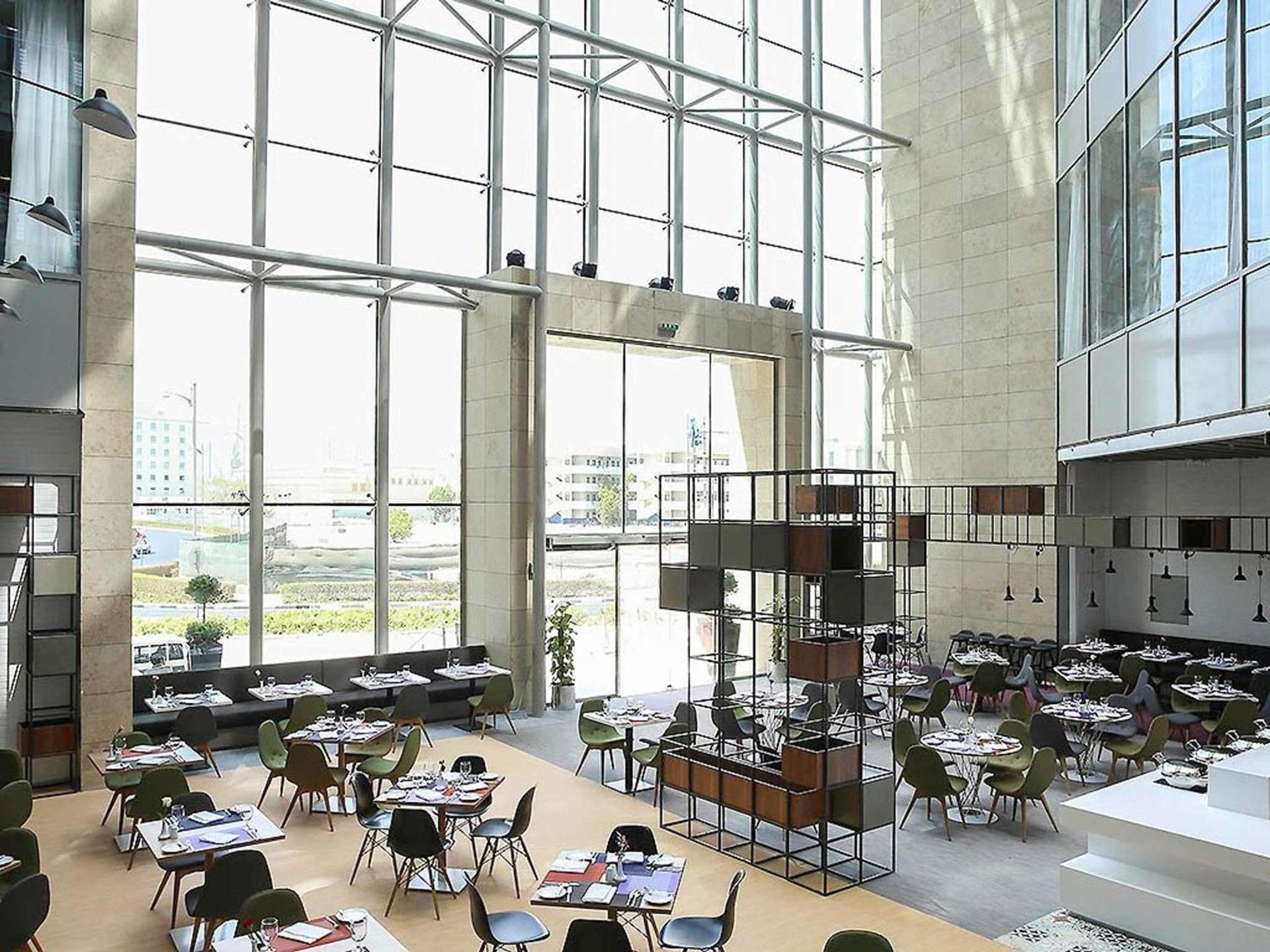 a large room with tables and chairs and large windows at Ibis Styles Dubai Jumeira in Dubai