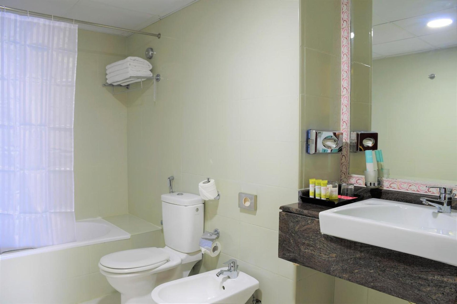 a bathroom with a toilet and a sink and a tub at Ramada by Wyndham Beach Hotel Ajman in Ajman 